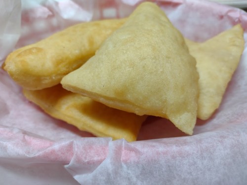 A basket lined with paper containing several golden-brown, flaky pastries.