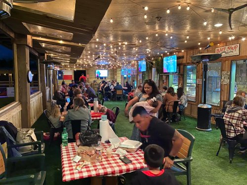 A lively outdoor dining area with string lights, families enjoying meals, and a casual atmosphere.