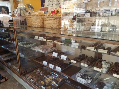 A display case filled with various chocolates and confections, with baskets of treats on top.