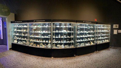 A display of glass cases filled with various rocks and minerals in a museum setting.