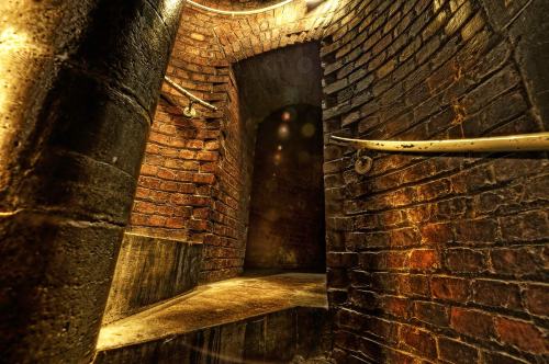 A dimly lit spiral staircase made of brick, leading to a dark archway.