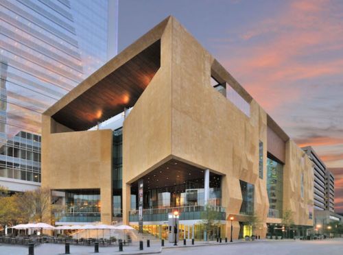 Modern architectural building with a unique geometric design, featuring large windows and a warm color palette at sunset.