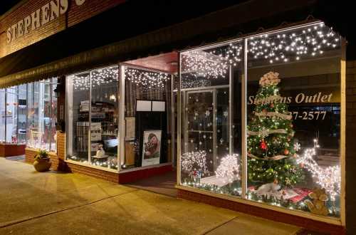 A festive storefront decorated with Christmas lights and a tree, showcasing holiday spirit in a cozy setting.