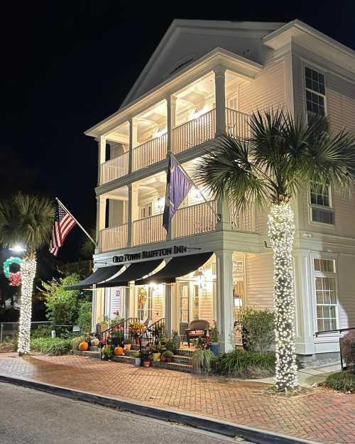 A charming inn at night, adorned with lights, pumpkins, and festive decorations, featuring palm trees and American flags.