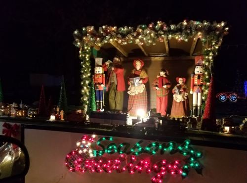 A festive display featuring holiday figures, nutcrackers, and lights, with "Season's Greetings" illuminated in front.