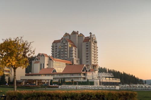 A large hotel building with a distinctive architectural design, surrounded by trees and a clear sky at sunset.