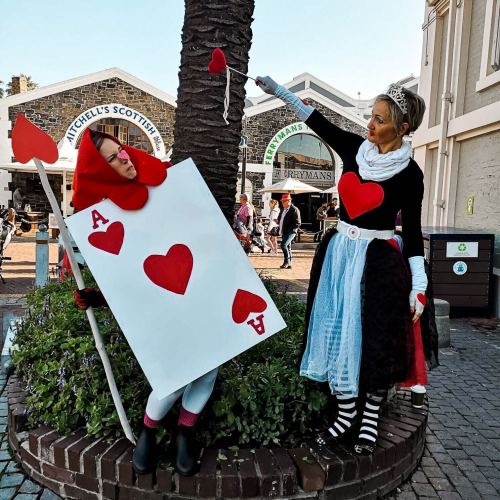 Two women dressed as playing cards pose by a tree, one as the Queen of Hearts and the other as the Ace of Hearts.