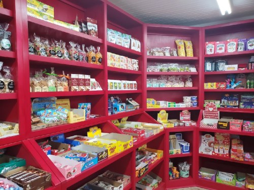 A colorful display of various snacks and candies on red shelves in a store.