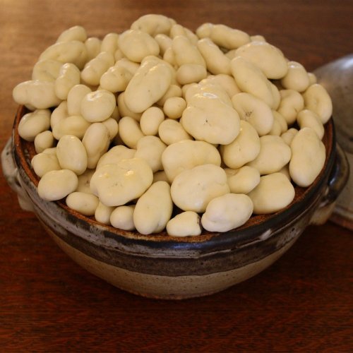 A bowl filled with small, pale, oval-shaped objects resembling white beans or stones.