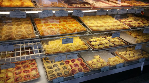 A display case filled with various pastries, including fruit tarts and cream-filled desserts, arranged on trays.