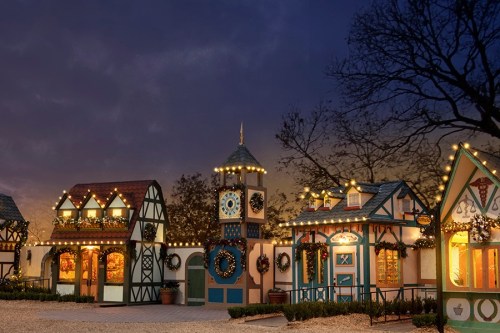 Charming festive village with decorated buildings and twinkling lights at dusk.