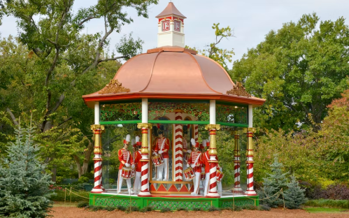 A festive gazebo with a copper roof, decorated with candy cane stripes and toy soldier figures inside.