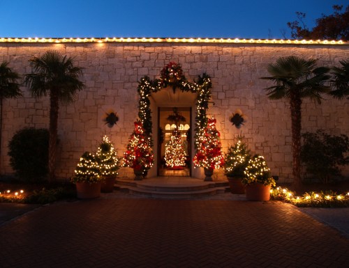 A beautifully decorated entrance with Christmas trees and lights, surrounded by palm trees and festive greenery.