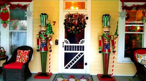 Two festive nutcracker figures stand by a decorated front door, surrounded by holiday wreaths and colorful decorations.