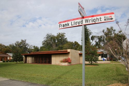 Sign for Frank Lloyd Wright Way in front of a modern building surrounded by green grass and trees.