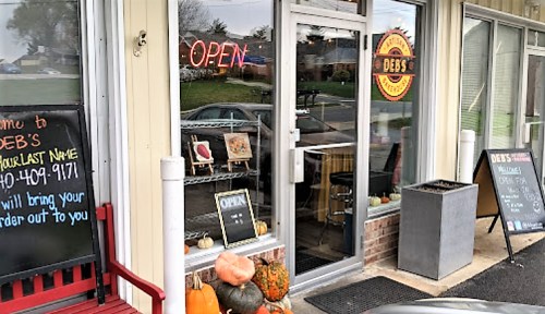 Exterior of Deb's restaurant with an "Open" sign, pumpkins, and chalkboards displaying menu items.