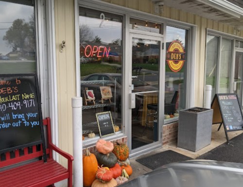 Exterior of Deb's restaurant with an "Open" sign, pumpkins, and a welcoming entrance.