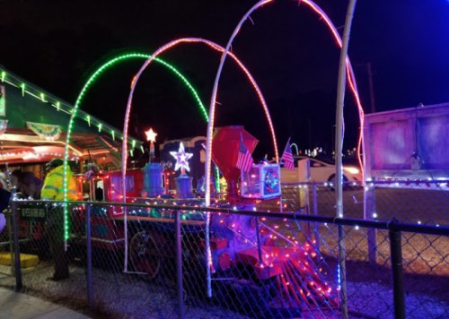 A brightly lit train display with colorful lights and decorations, set against a night sky.