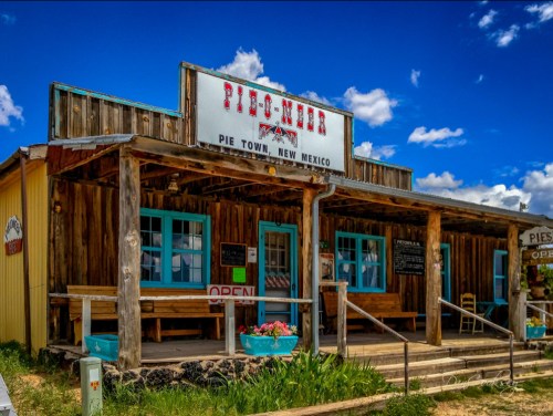 A rustic pie shop in Pie Town, New Mexico, featuring a wooden facade and bright blue windows under a blue sky.