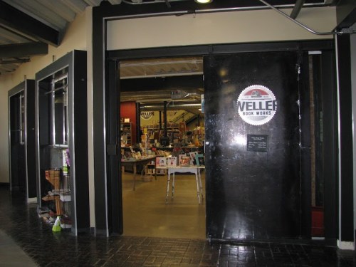 Entrance to Weller Book Works, featuring a black door and a sign, with shelves visible inside.