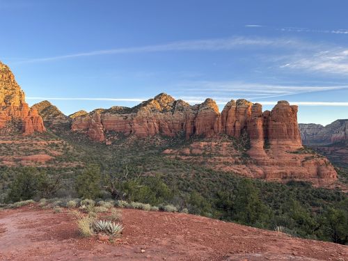 A scenic view of red rock formations and green vegetation under a clear blue sky in a desert landscape.