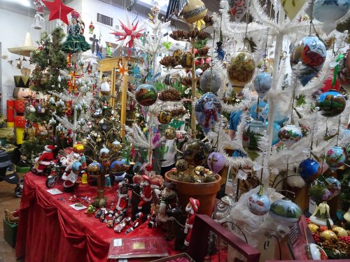 A festive display of Christmas decorations, including ornaments, trees, and holiday figurines in a colorful shop.