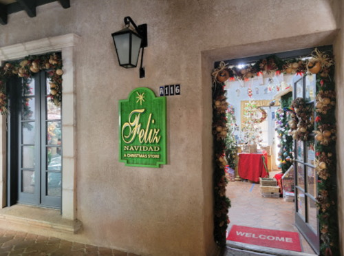 A festive entrance to "Feliz Navidad," a Christmas store, adorned with holiday decorations and a welcoming sign.