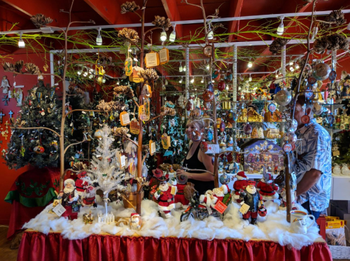 A festive display of holiday decorations and ornaments, with two people browsing among the items.