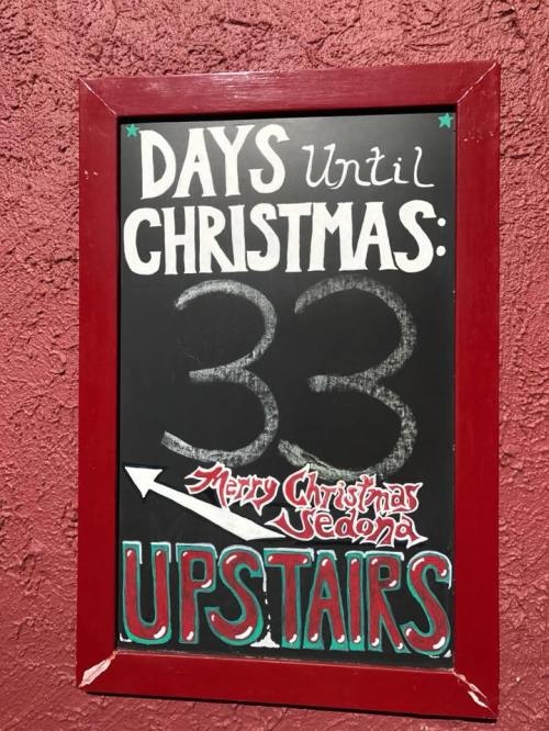 Chalkboard sign showing "33 Days Until Christmas" with an arrow pointing "Upstairs" and "Merry Christmas Sedona."
