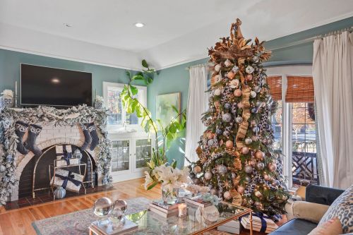 A cozy living room decorated for the holidays, featuring a beautifully adorned Christmas tree and a festive fireplace.