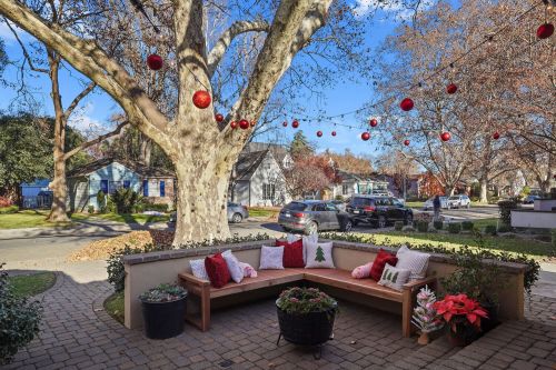 Cozy outdoor seating area with festive decorations, surrounded by trees and houses on a sunny day.