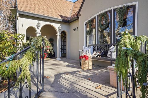 A festive porch decorated with greenery and holiday accents, featuring a welcoming entrance and large windows.