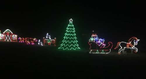Colorful Christmas lights display featuring a tree, sleigh, and festive figures against a dark background.