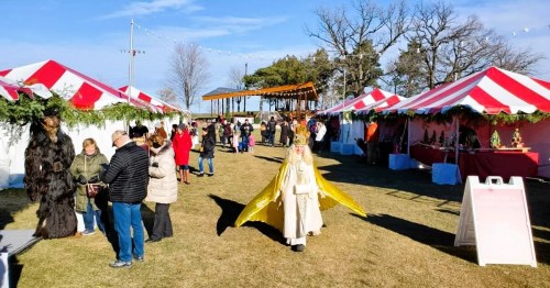 A festive outdoor market with colorful tents, people browsing, and a person in a yellow cape walking through the scene.