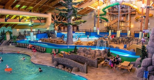 Indoor water park featuring slides, a lazy river, seating areas, and children playing in the water.