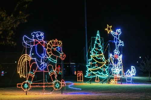 Colorful Christmas lights display featuring a bear on a horse, a Christmas tree, and a star-topped figure.