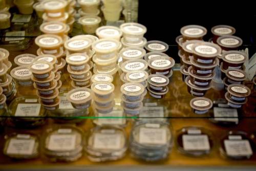 A display of various small containers filled with different sauces or condiments, neatly arranged on a shelf.