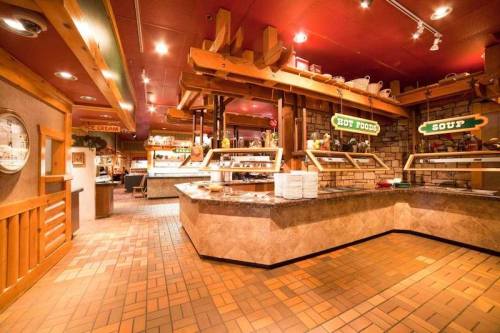 Interior of a cozy restaurant featuring a buffet area with signs for soup and hot food, warm lighting, and wooden accents.