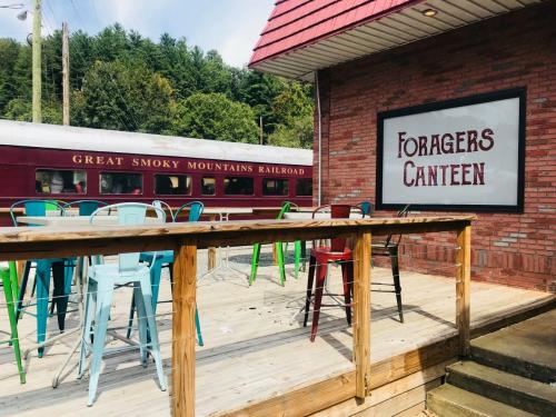 Outdoor seating area at Foragers Canteen, with a vintage train and lush green mountains in the background.