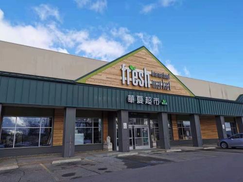 Exterior of Fresh International Market, featuring a wooden facade and large signage against a blue sky.