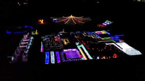Aerial view of a vibrant display of colorful lights arranged in various patterns against a dark background.
