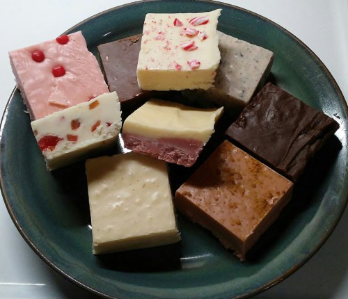A colorful assortment of fudge pieces arranged on a green plate, featuring various flavors and toppings.