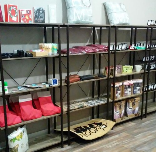 Shelves displaying various home goods, including pillows, cards, and decorative items in a cozy retail space.
