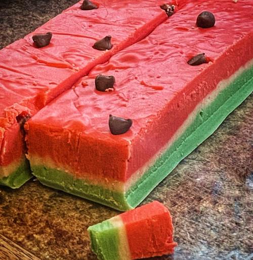 Colorful layered fudge resembling a watermelon, with red and green sections topped with chocolate chips.