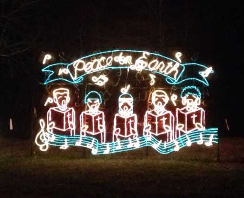 Colorful holiday lights depicting five figures singing under a banner that reads "Peace on Earth."