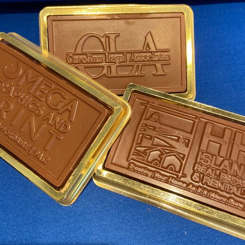 Three chocolate bars with embossed logos: Carolina Legal Associates, Omega Signs and Print, and a real estate company.