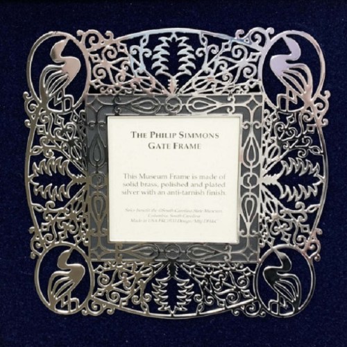 A decorative silver gate frame with intricate designs, featuring a plaque that reads "The Philip Simmons Gate Frame."