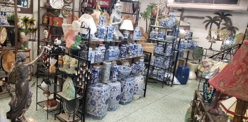 A vibrant display of decorative items, including blue and white vases, sculptures, and lamps in a cozy shop setting.