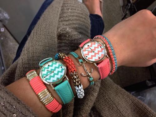 A close-up of a wrist adorned with colorful bracelets and a watch featuring a chevron pattern.