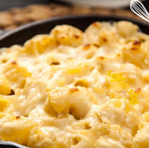 Creamy, cheesy baked macaroni and cheese in a cast iron skillet, golden and bubbling on top.